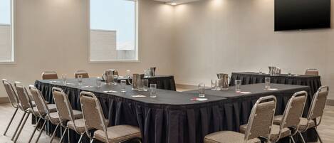 Un salón de conferencias con una mesa larga, sillas y un televisor de pantalla plana en la pared.