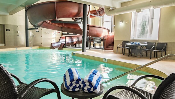 Ein Hallenbad mit Wasserrutsche, Liegestühlen und einem Tisch mit Handtüchern.