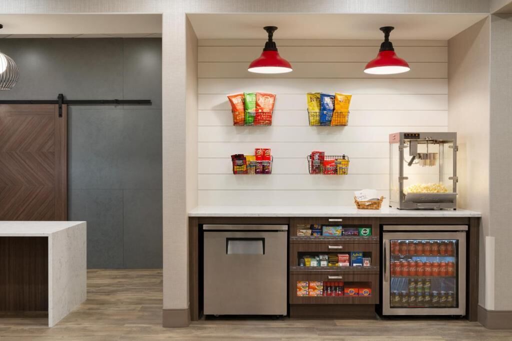 A snack bar with a refrigerated display, a coffee machine, and a small refrigerator.