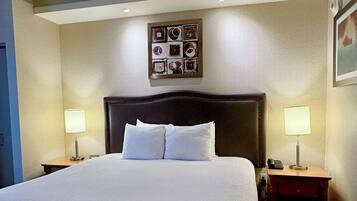 A hotel room with a large bed, two bedside lamps, a nightstand with a phone, and a framed picture on the wall.