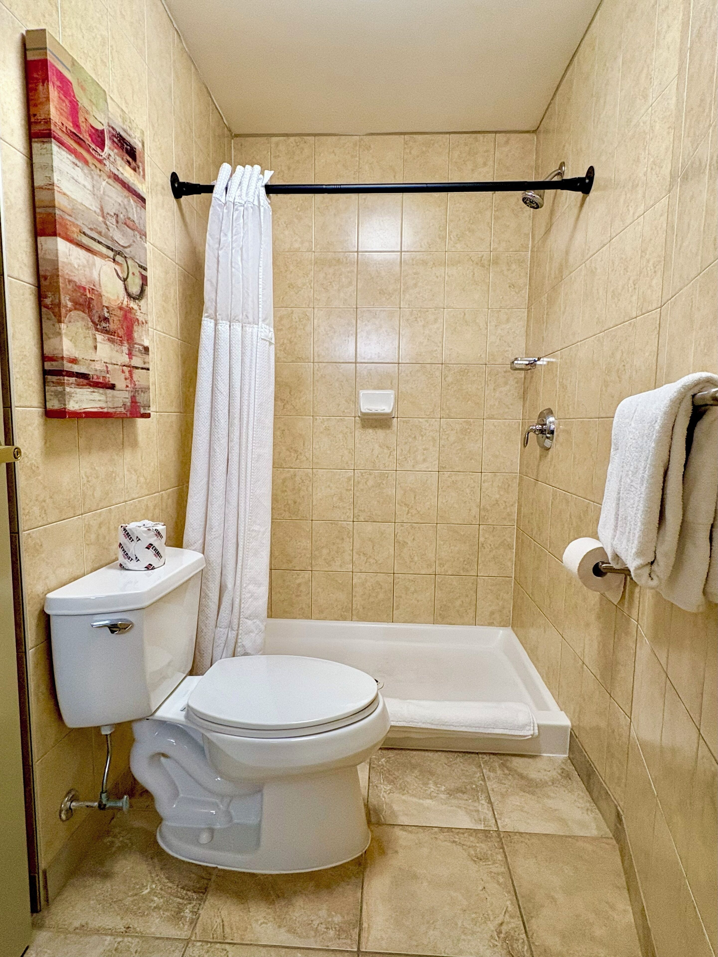 A small bathroom with a toilet, shower, and a towel rack.