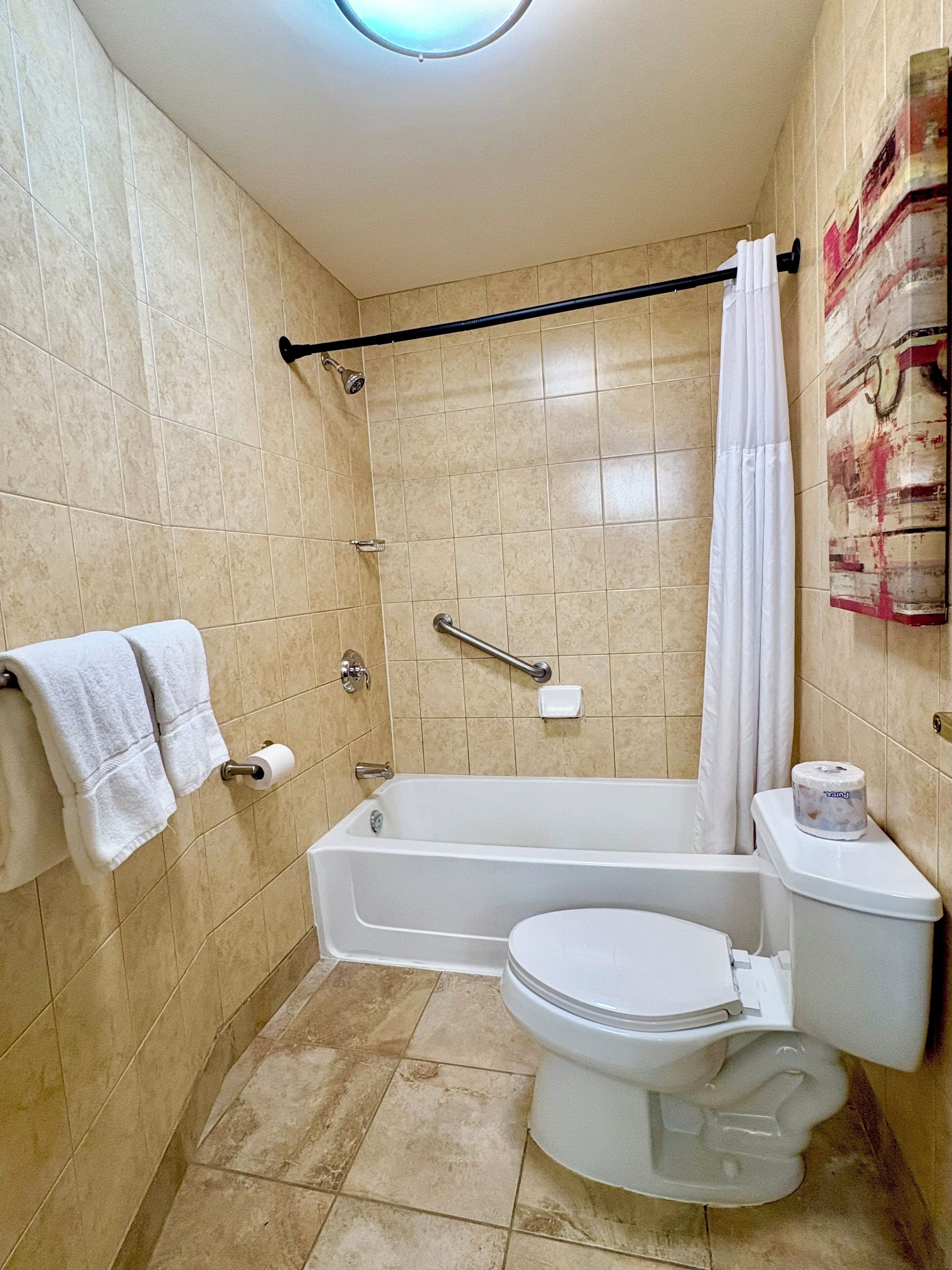 A bathroom with a bathtub, toilet, and a shower area.