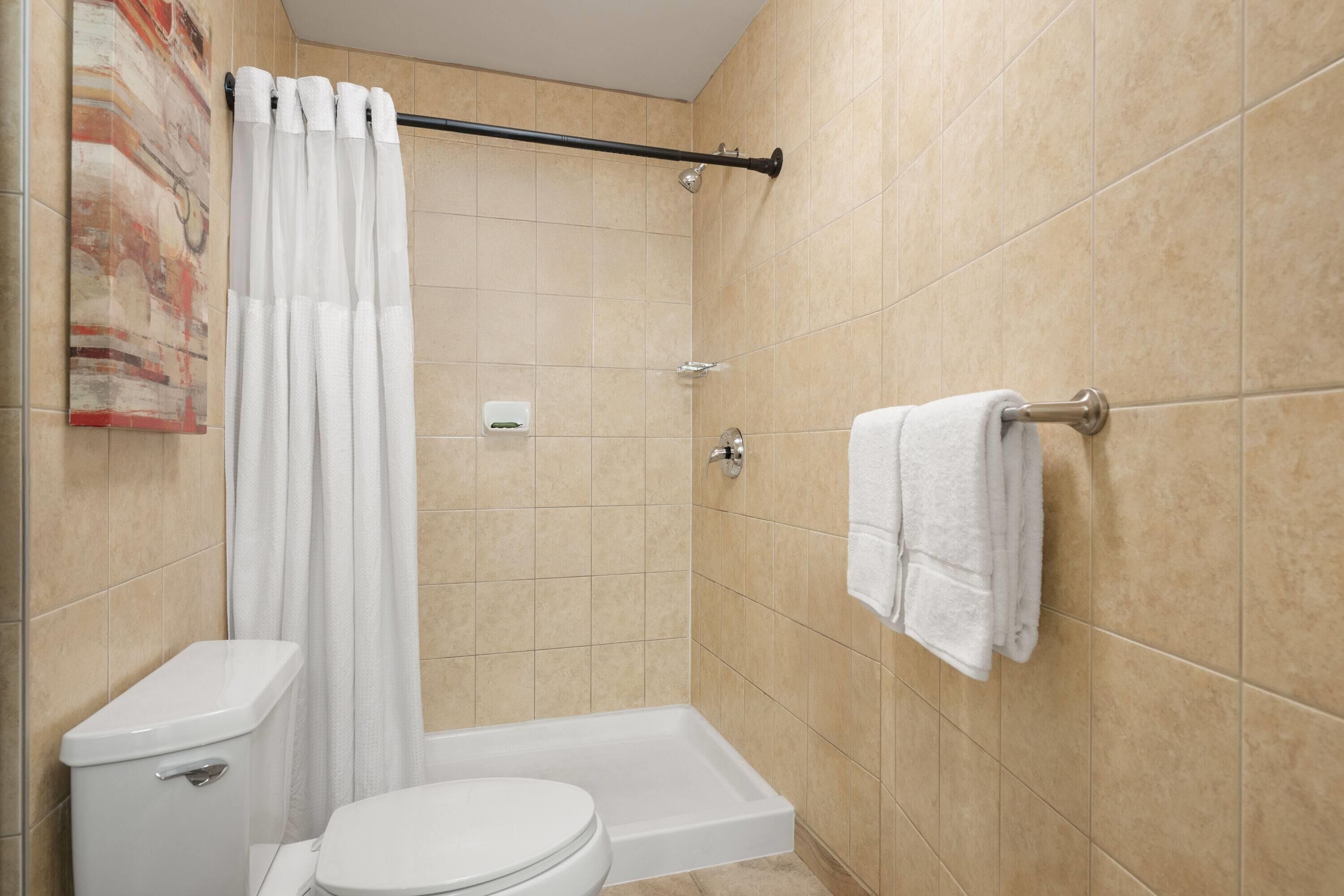 A bathroom with a shower, toilet, and towel rack.