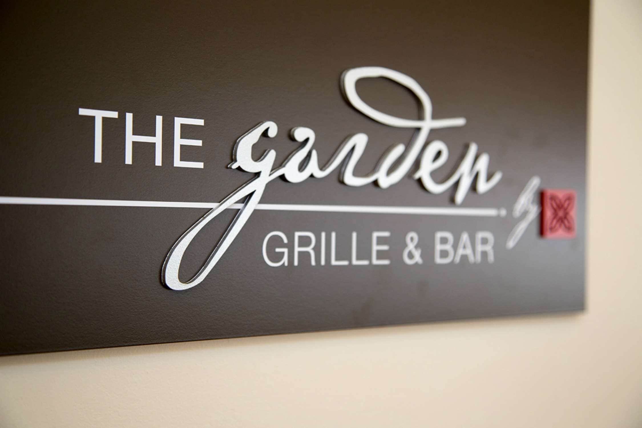 En skylt för ”The Garden Grille & Bar” med en minimalistisk design och en röd symbol som visar att något är förbjudet.