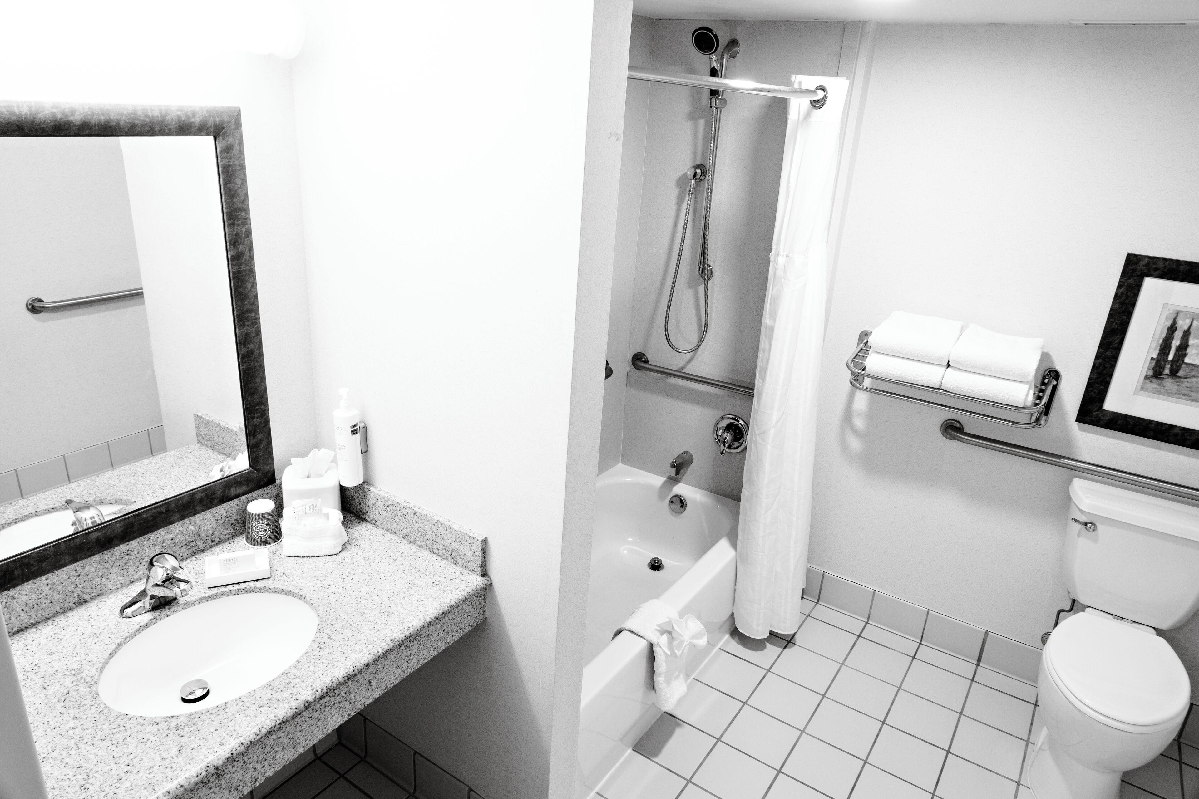 A bathroom with a sink, mirror, shower, toilet, and towel rack.