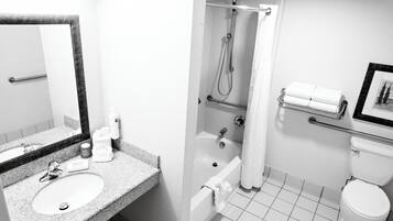 A bathroom with a sink, mirror, shower, toilet, and towel rack.