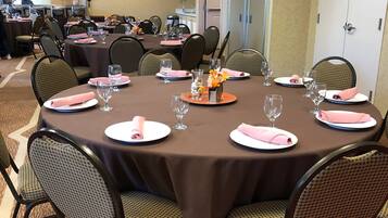A conference room with round tables, chairs, and a carpeted floor.