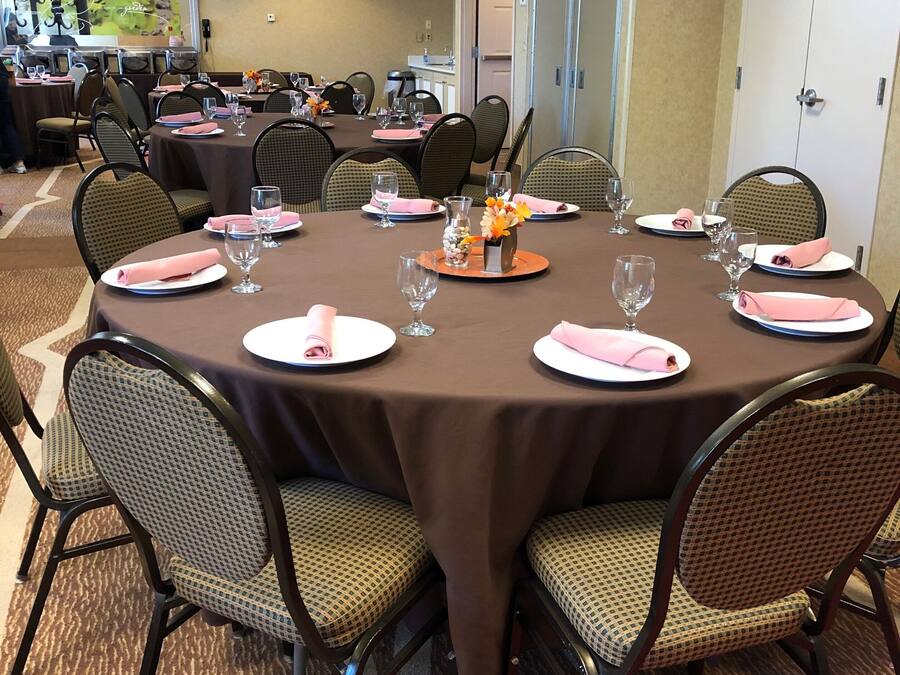 A conference room with round tables, chairs, and a carpeted floor.