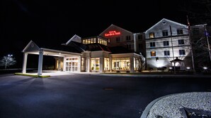 Un hôtel reconnaissable à son grand panneau « Hilton Garden Inn », doté d’un parking couvert et d’une entrée bien éclairée.