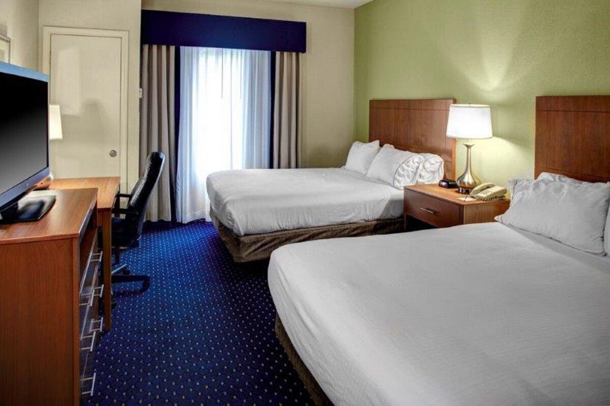 Habitación de hotel con dos camas, un escritorio con televisor, una lámpara y un teléfono.