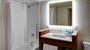 A bathroom with a bathtub, a sink, a mirror, and a toilet.