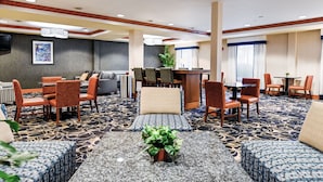 A hotel lobby with a seating area, a reception desk, and a television on the wall.