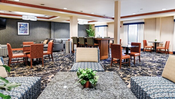 A hotel lobby with a seating area, a reception desk, and a television on the wall. - Holiday Inn Express Hotel & Suites Richmond North Ashland by IHG (Ashland)