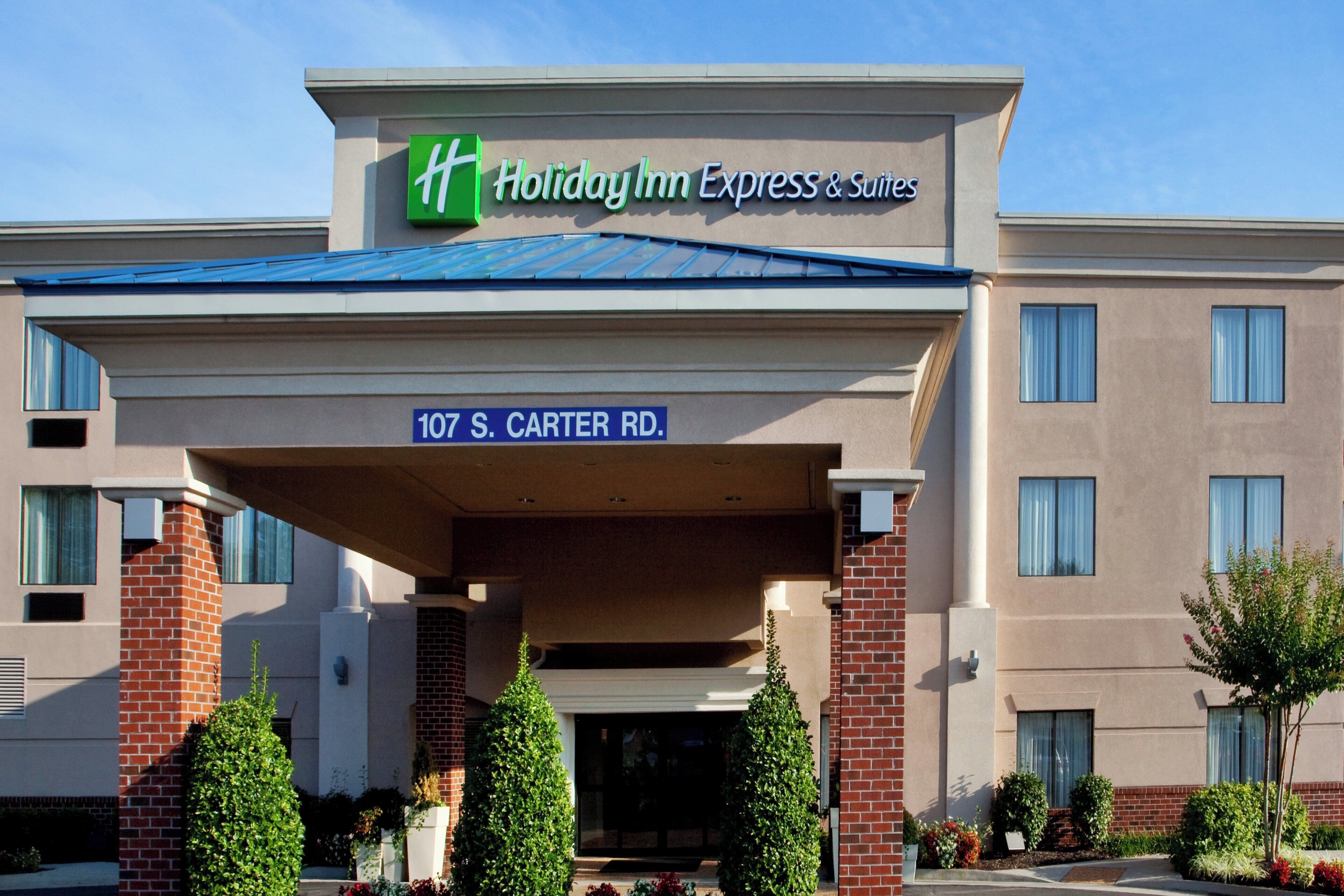 A Holiday Inn Express & Suites building with a clear sign indicating the address 107 S. Carter Rd.