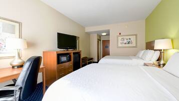 A hotel room with a bed, a desk with a computer, a television, and a chair.