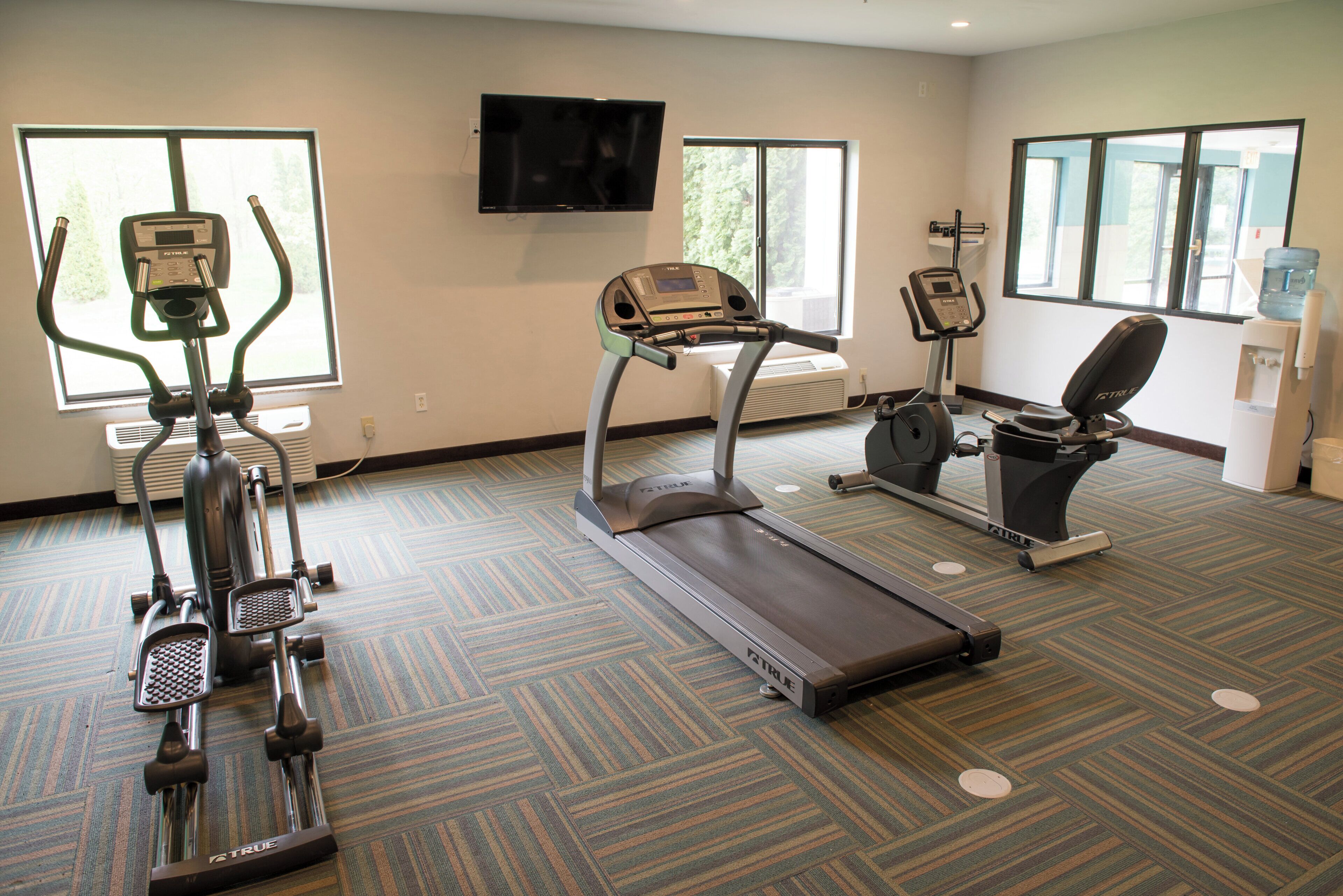 Et fitnesscenter med løbebånd, crosstrainer og motionscykel.