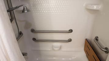 Un baño con ducha, barras de apoyo y panel de madera.