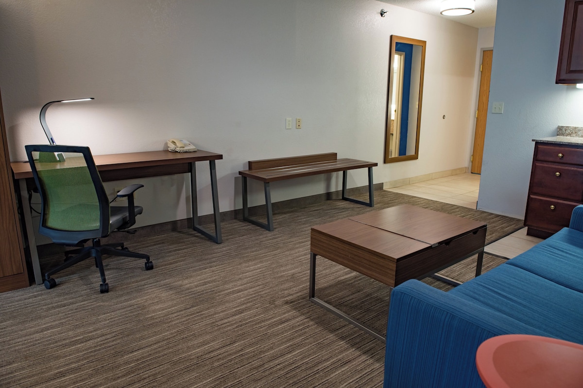 A furnished room with a desk, chair, bench, and a sofa.