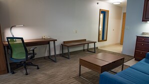 A room with a desk, chair, bench, and a blue sofa. - Holiday Inn Express & Suites Elkhart by IHG (Elkhart)