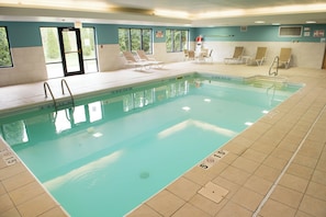 An indoor swimming pool with clear water, marked depth lines, and a tiled floor.