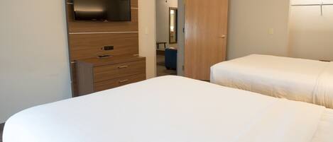 A hotel room with a large bed, a wooden dresser with a flat-screen TV, and a wardrobe.