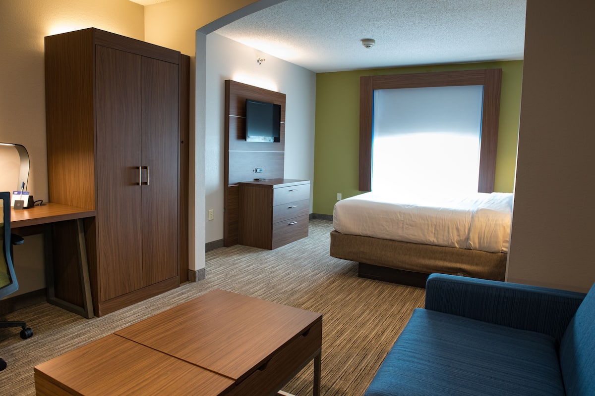 Una habitación de hotel con cama, escritorio, armario, cómoda y televisor.