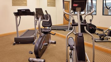 A fitness center with treadmills, elliptical machines, and a mirrored wall.