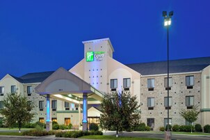 A Holiday Inn Express & Suites hotel with a modern design, featuring a prominent entrance and a covered walkway.