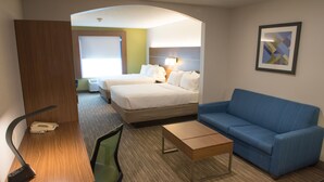 A hotel room with a bed, a blue sofa, a desk with a lamp, and a small table. - Holiday Inn Express & Suites Elkhart by IHG (Elkhart)