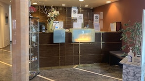 Una zona de recepción con un mostrador de mármol, una vitrina de vidrio y una planta en maceta.