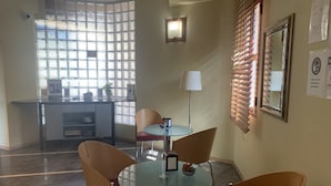 Un comedor moderno con una mesa de vidrio y sillas, una máquina de café y una planta decorativa.