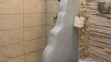 Un baño con diseño moderno, que destaca por una bañera de forma original y una pared con textura.