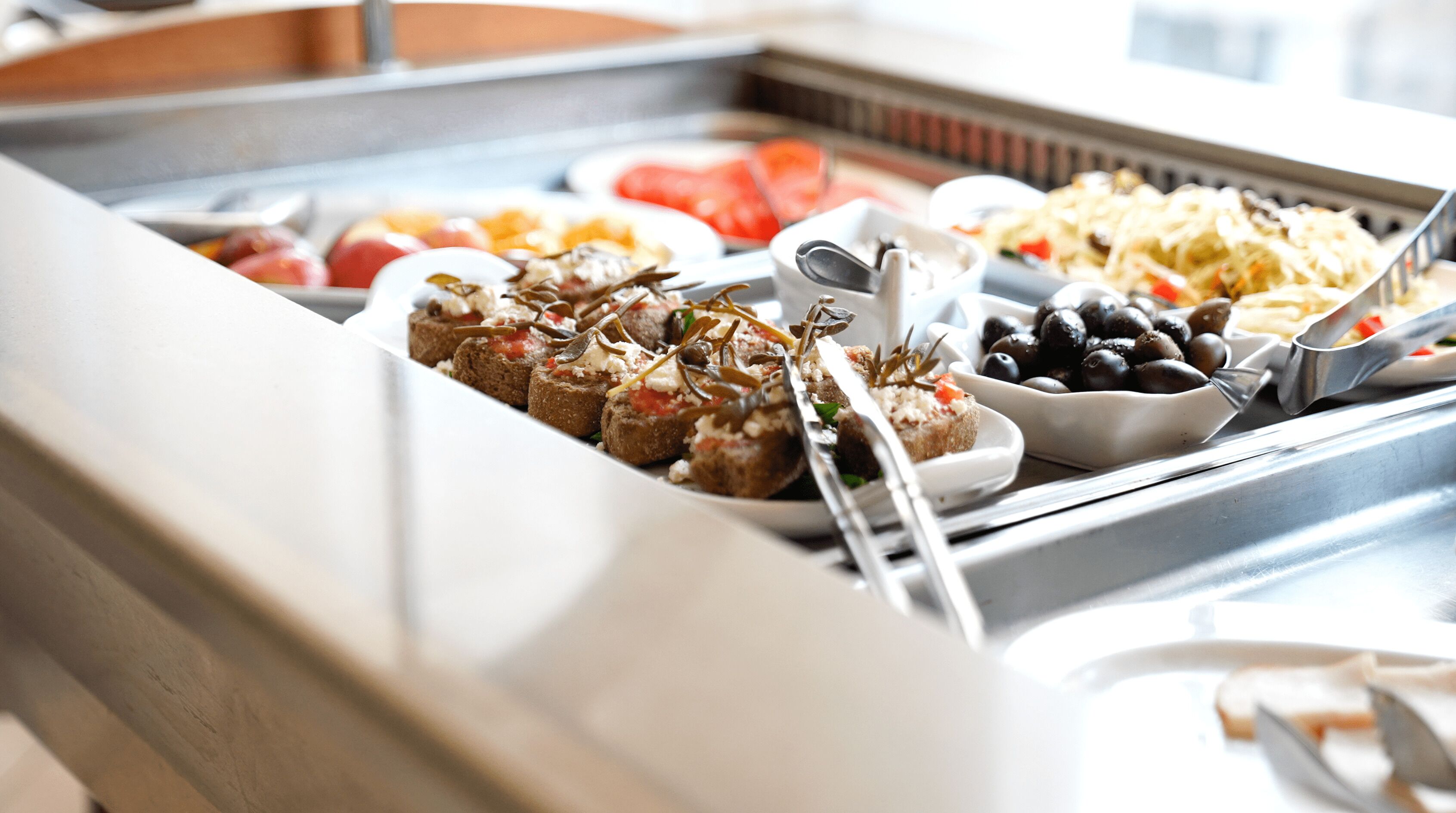 A buffet with various food items including bread, olives, and a salad.