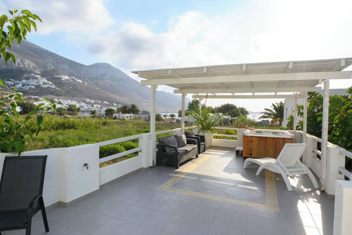 Eine überdachte Terrasse im Freien mit einer Couch, Stühlen und einem Whirlpool.