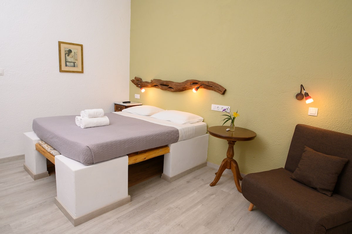 Ein Schlafzimmer mit einem Bett, einem Nachttisch und einem braunen Sofa.