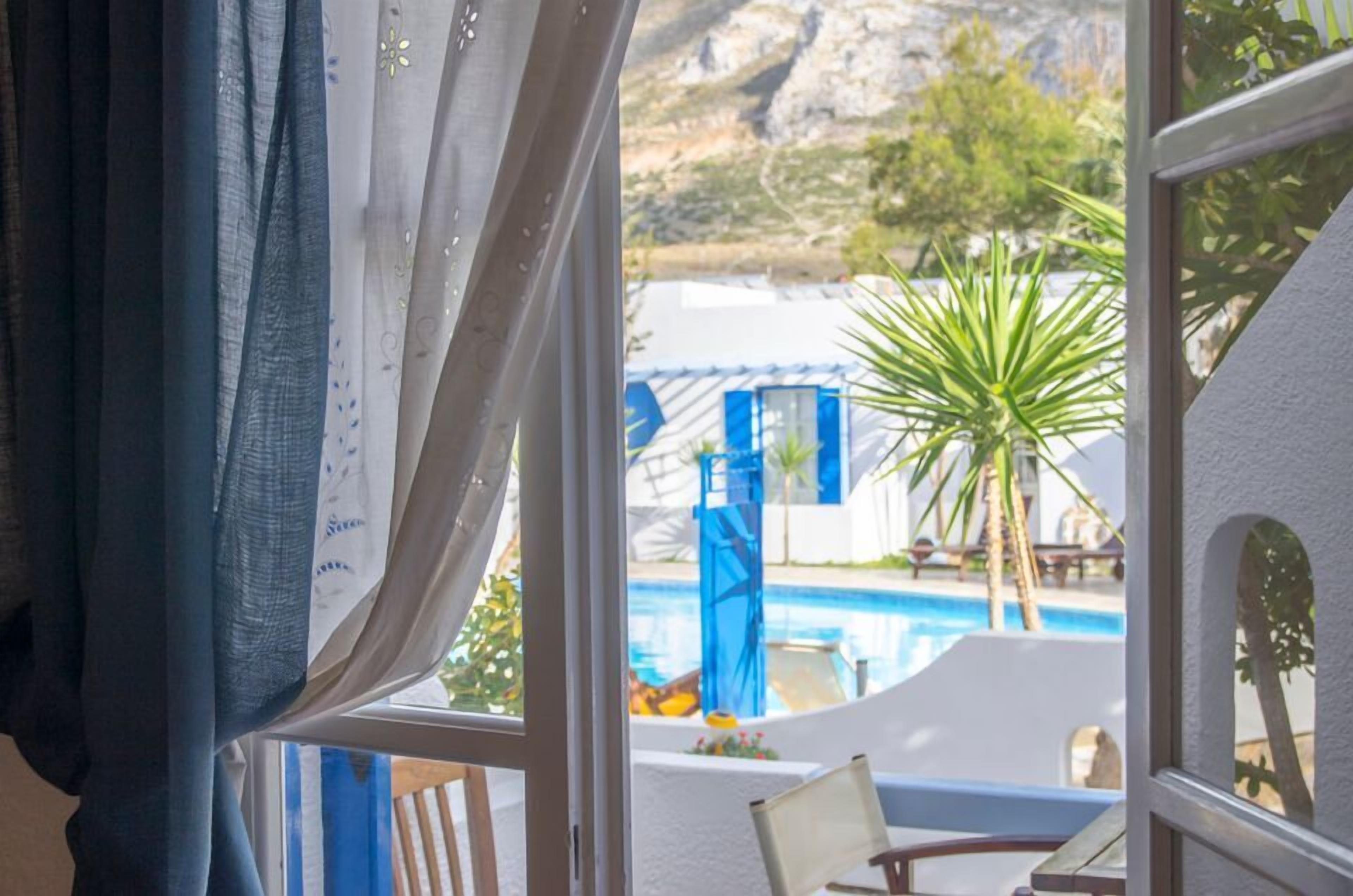 Habitación con vista a una piscina, una palmera y un paisaje montañoso.