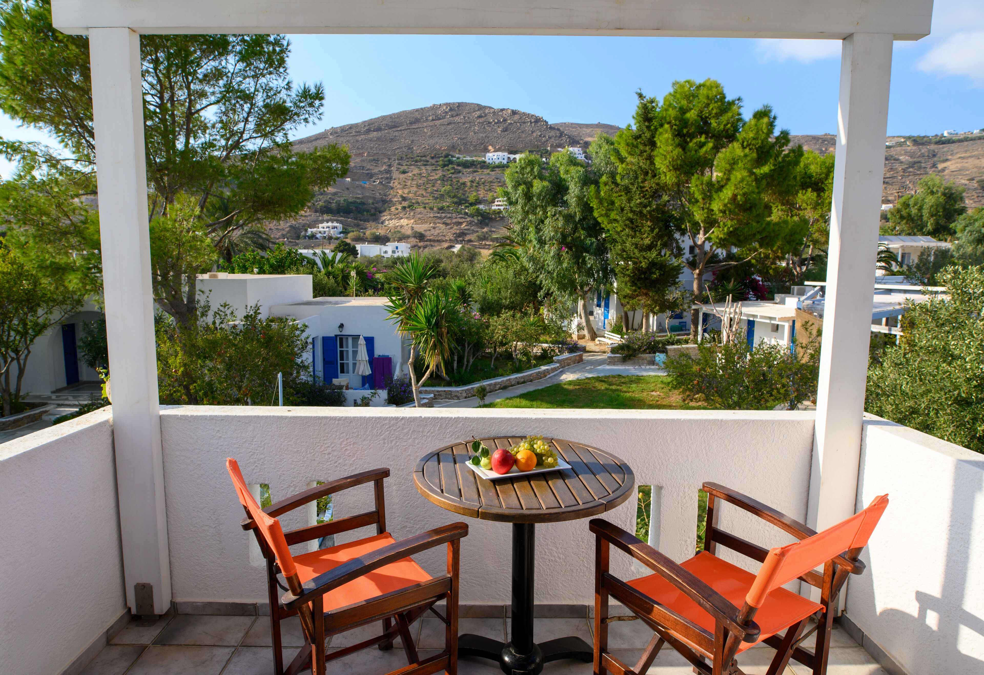 A balcony with two wooden chairs and a small table with fruit.