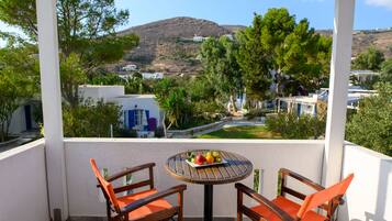 A balcony with two wooden chairs and a small table with fruit.