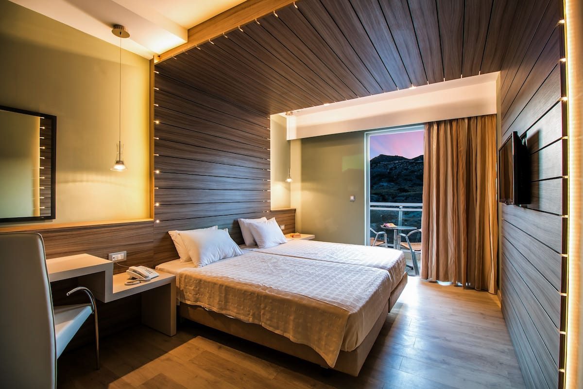 Une chambre d’hôtel moderne avec un grand lit, des tables de chevet, un bureau et une télévision.