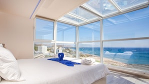 Habitación de hotel con una cama grande, vista al océano y tragaluz.