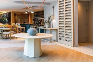 A modern interior with a round table, chairs, a bar area, and a shelving unit. - Sanctuary South Beach (MIAMI BEACH)