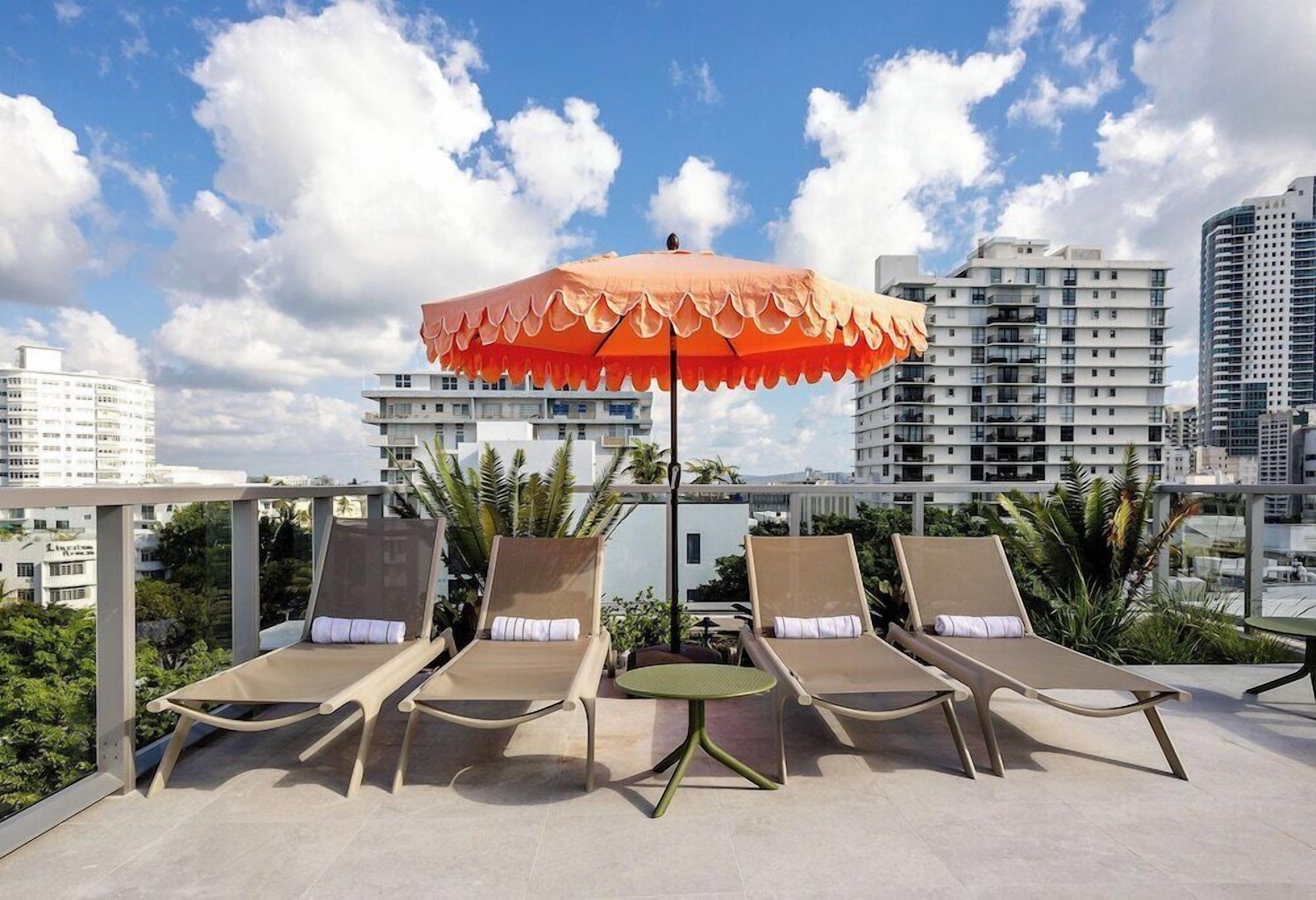 Un espace de détente aménagé sur le toit, comprenant deux chaises longues, une table et un parasol.