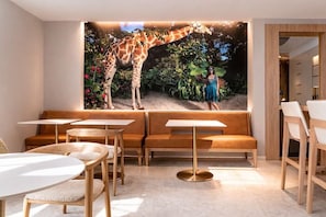 A restaurant with a mural of giraffes, wooden furniture, and a modern interior design.