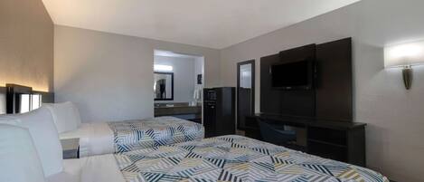 Habitación de hotel con dos camas, televisión, escritorio y espejo.
