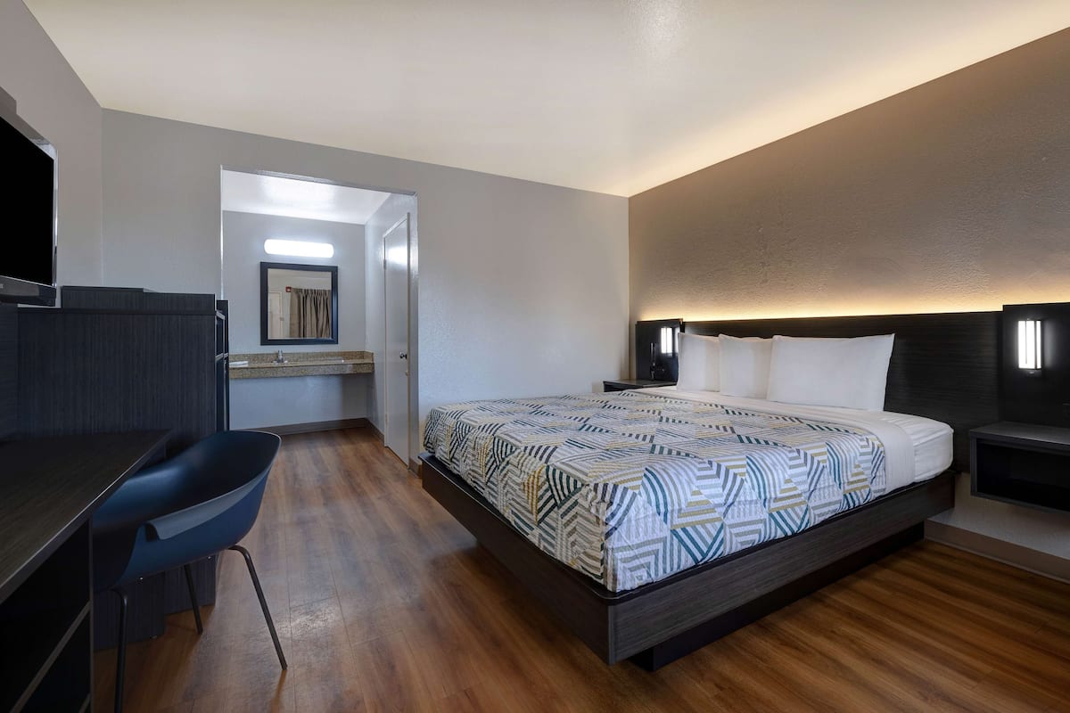A modern hotel room with a bed, a desk, and a chair.