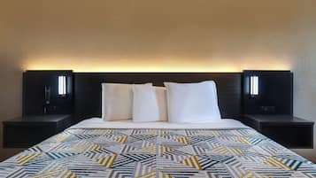 Una habitación de hotel con una cama grande, dos mesitas de noche y un cabecero con iluminación integrada.
