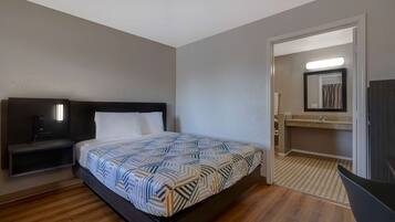 A hotel room with a bed, bedside table, and a bathroom visible through an open door.