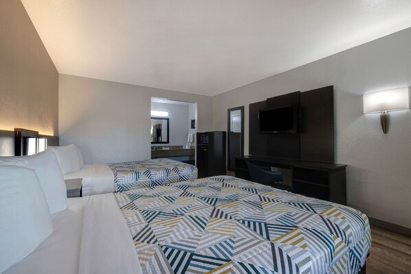A hotel room with two beds, a TV, a desk, and a mirror. - Motel 6 Buttonwillow, CA Central (Buttonwillow)