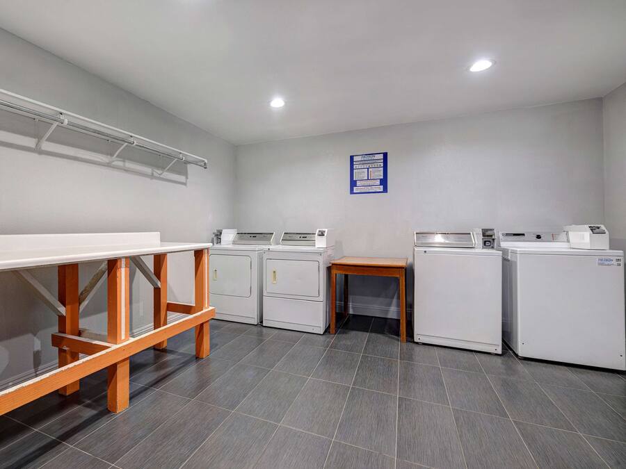 A laundry room with a long counter, two washing machines, and a dryer.