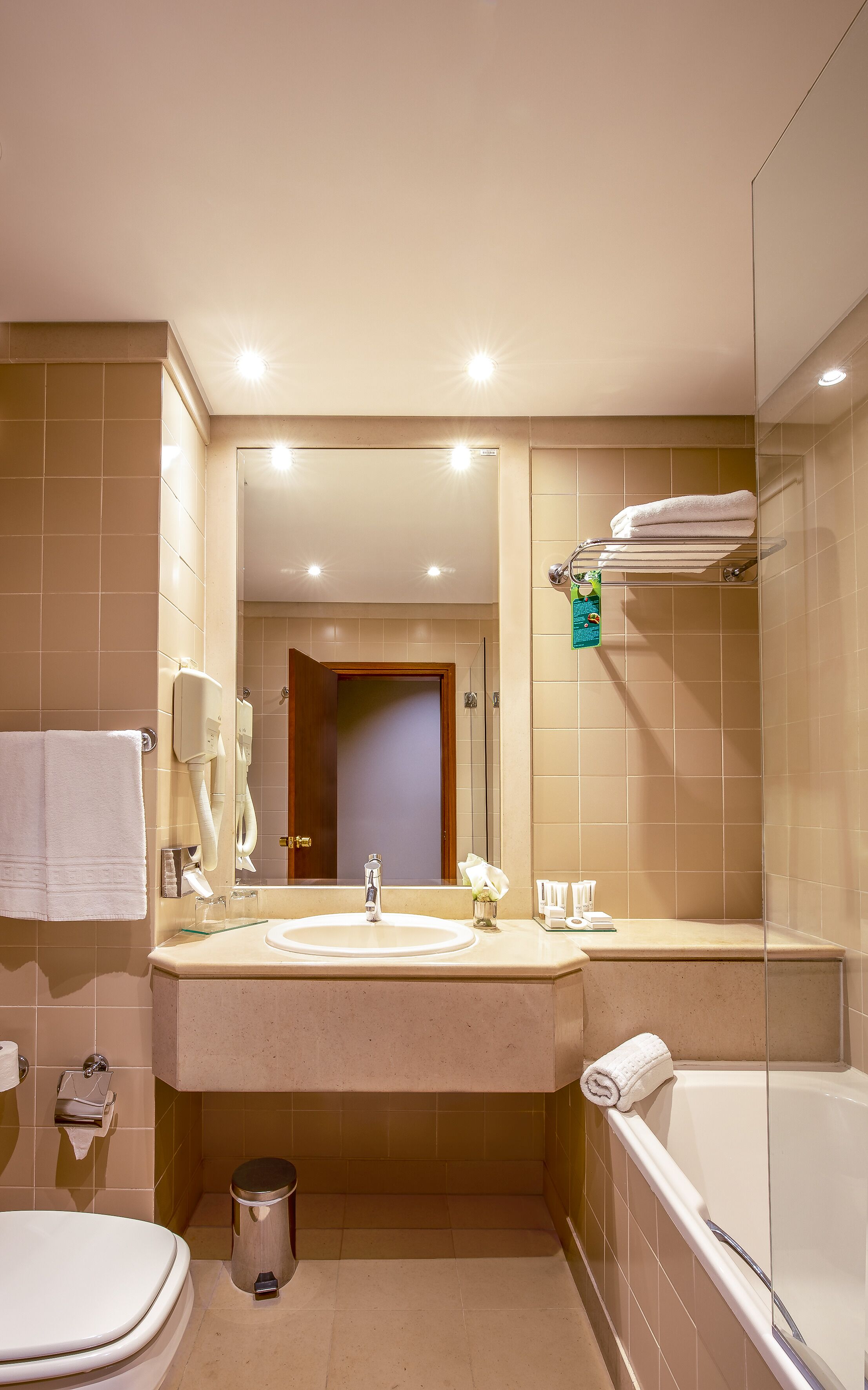 A modern bathroom with a large mirror, dual sinks, a toilet, and a bathtub.